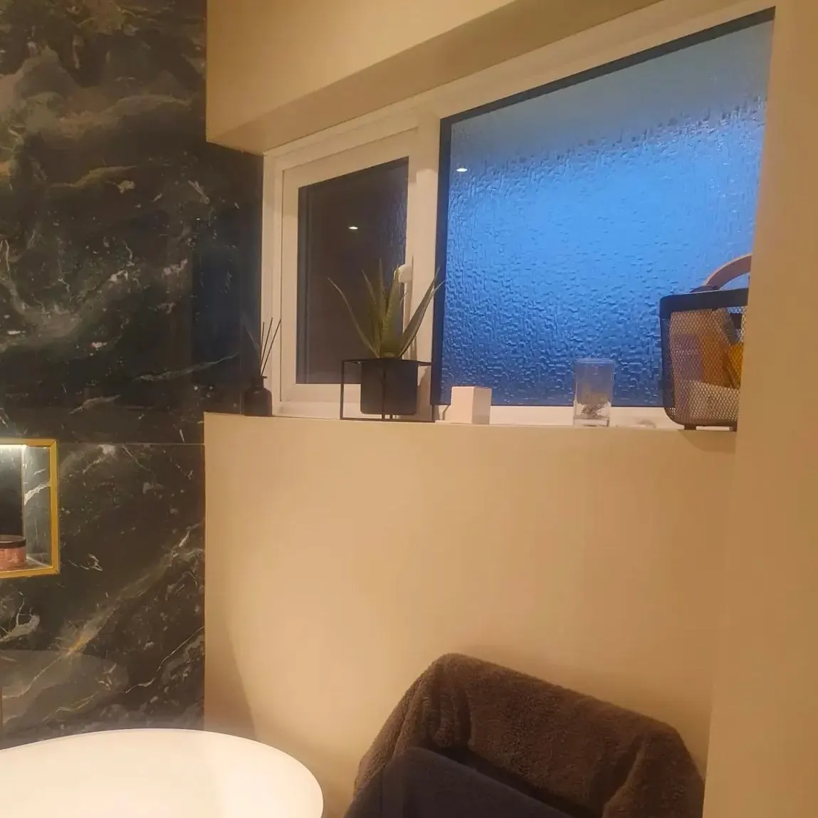 Seamless microcement wall and window reveal beside a dark marble feature wall