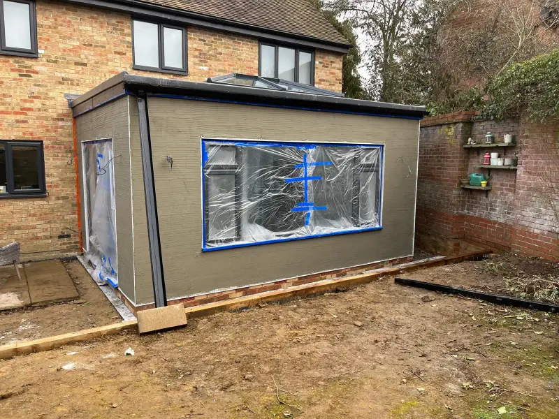 Before: the same extension with a bare grey base coat and windows covered in protective plastic