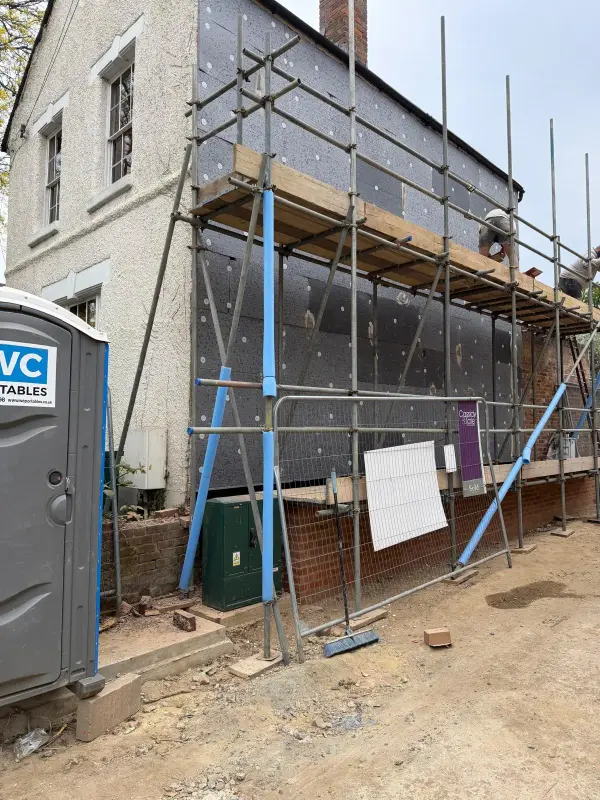 Stage 1: Gable wall under scaffolding covered in grey insulation boards with white fixings