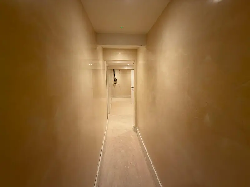 Narrow hallway with warm polished Venetian plaster walls catching the light
